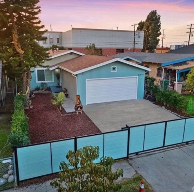 Front of the house: a teal single-family home with a gated driveway and two-car garage